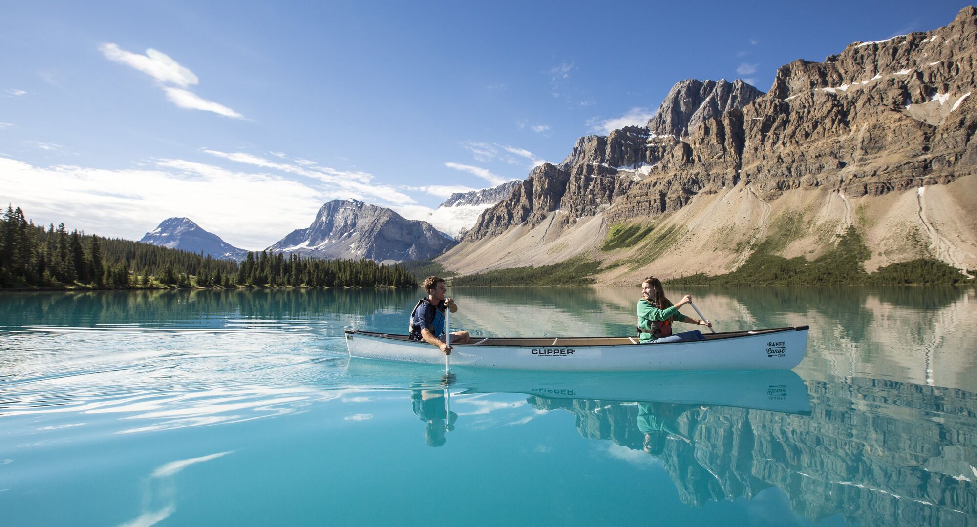People paddling in a canoe on the turquoise waters of Bow Lake in the summer